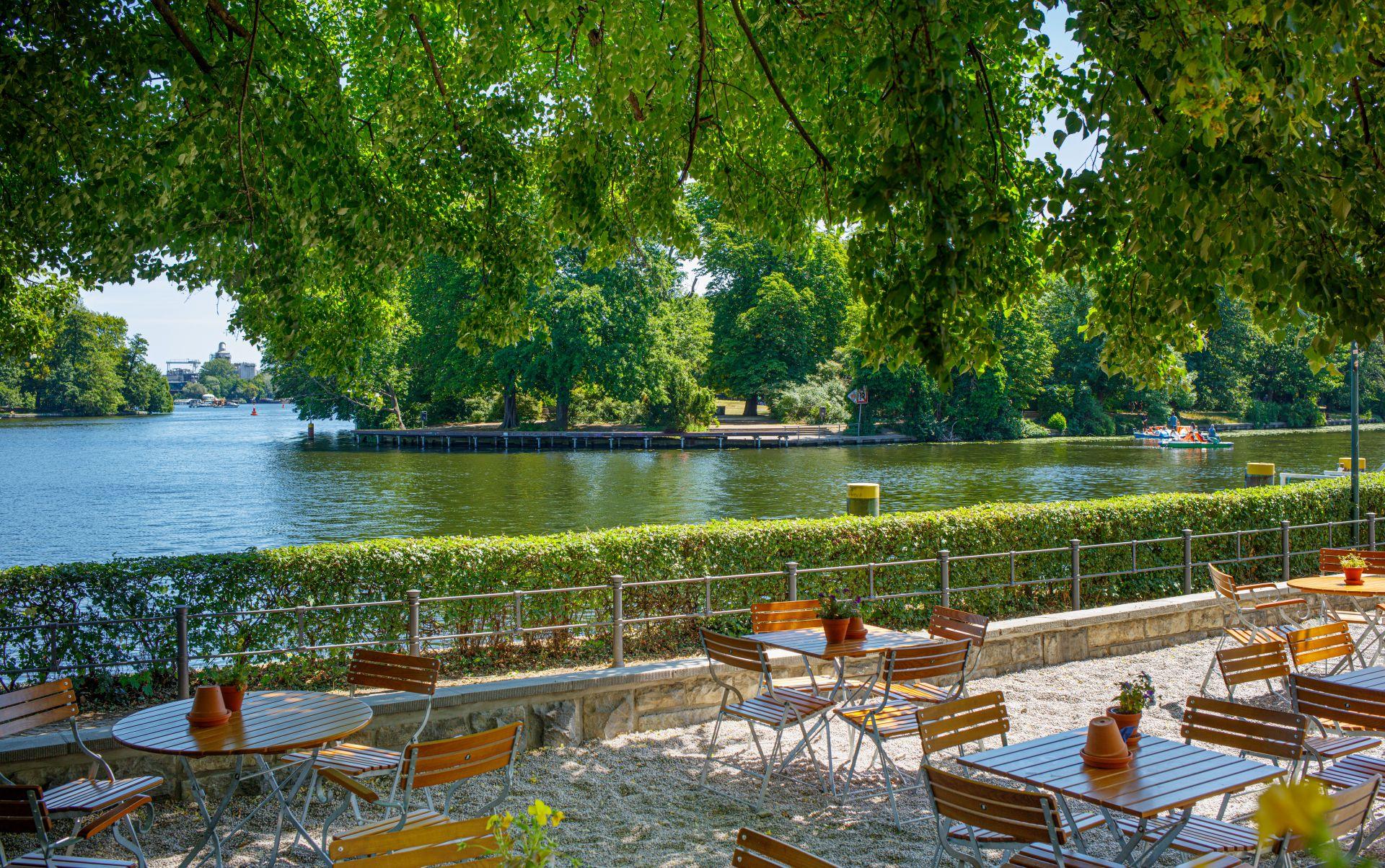 Ruhiger Biergarten am Ufer der Spree mit leeren Sitzplätzen – beliebter Ort für Alleinreisende oder Treffen über Escort Berlin